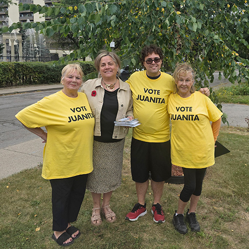 Juanita with 3 campaign volunteers with wearing yellow t-shirts that say Vote Juanita. Standing outdoor with arms around each other.