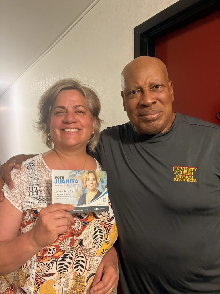 Juanita next to former Hamilton Tiger-Cat Art Tolliver, holding her canvassing literature and big smiles.